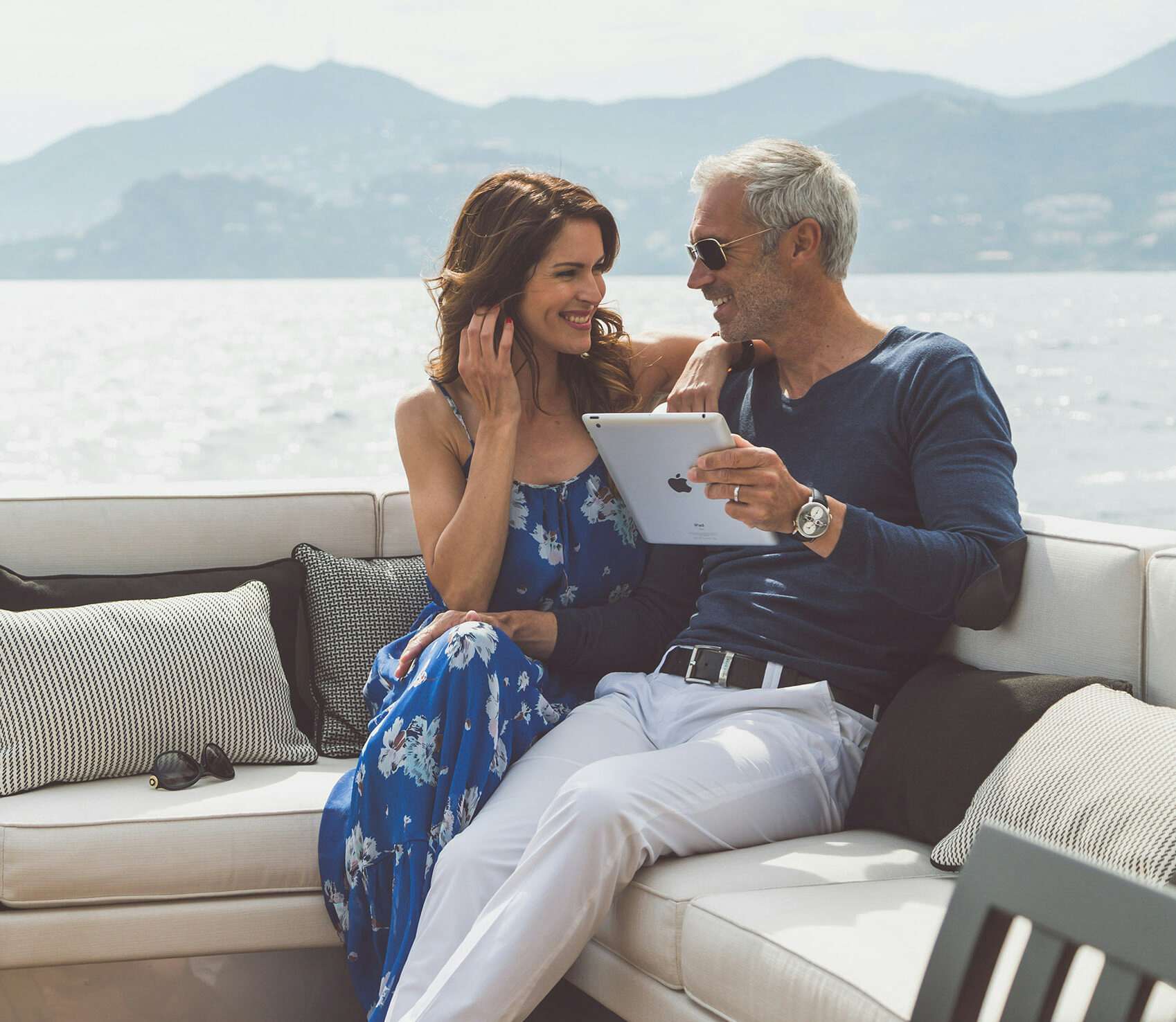 Couple sitting on yacht deck with tablet in hand