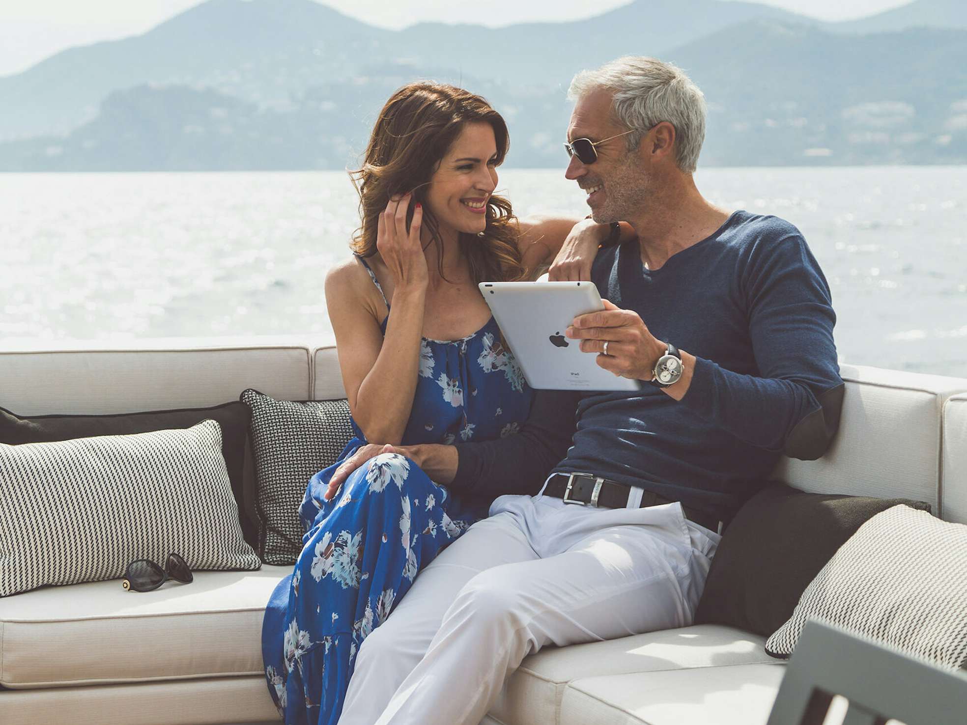 Couple sitting on yacht deck with tablet in hand