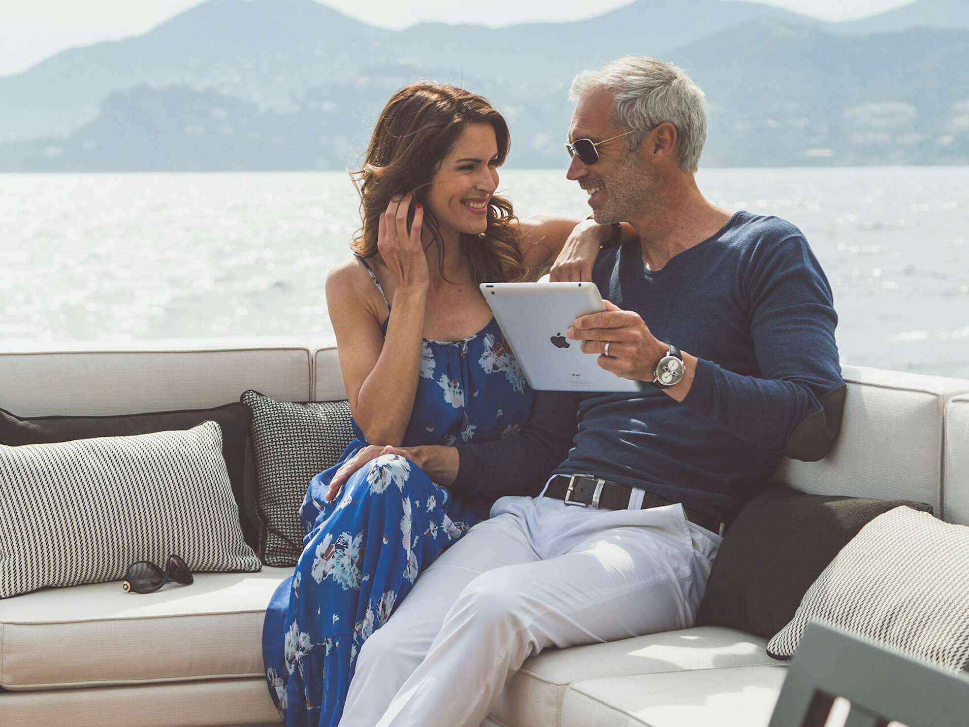 Concierge Services Couple sitting on yacht deck with tablet in hand