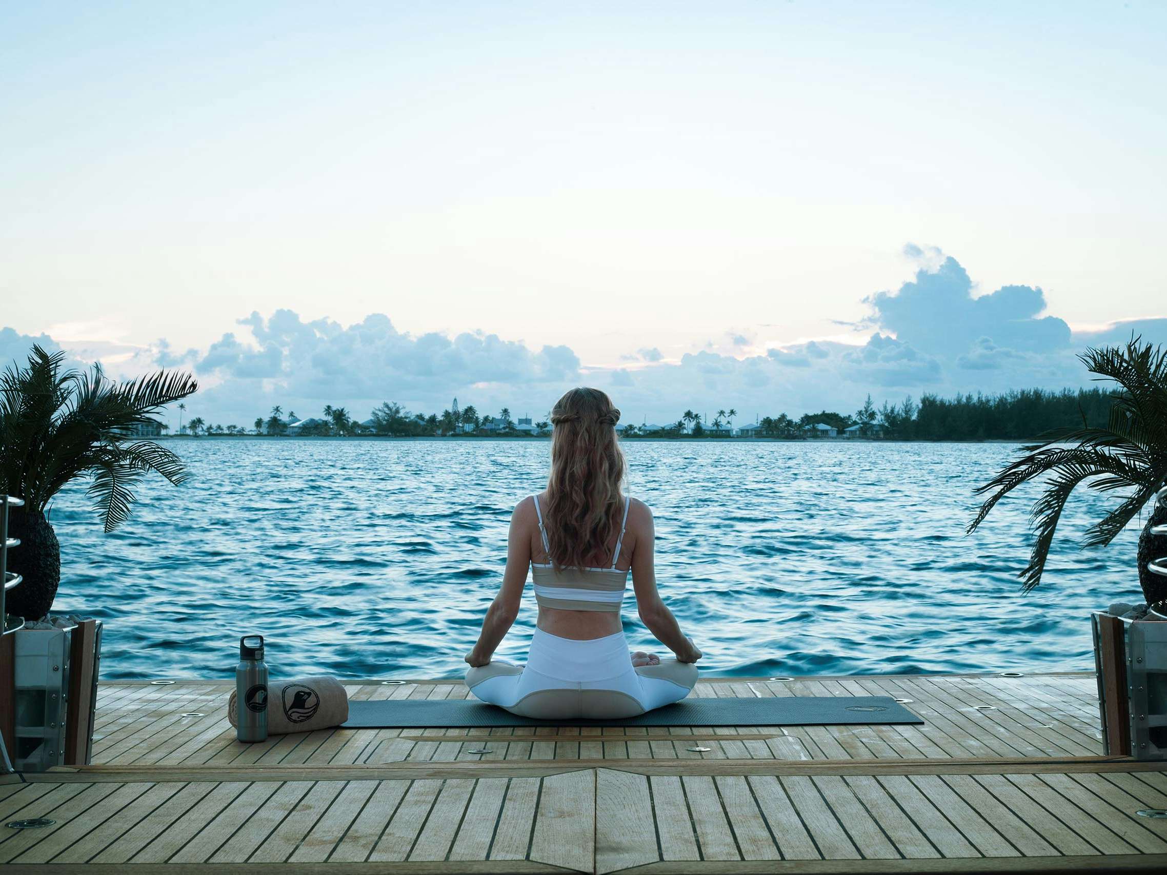 Concierge-Services_Health-Yoga Woman doing yoga at sunrise from on swim platform of superyacht, looking out at sea