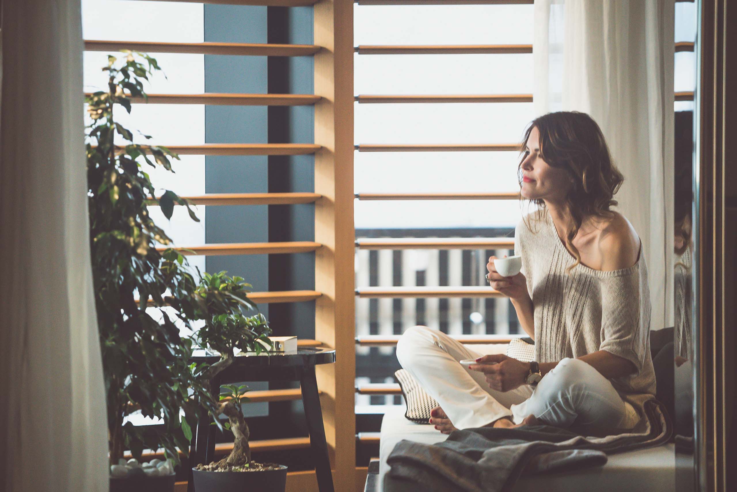 Lady holding a cup of tea while looking out the superyacht's window