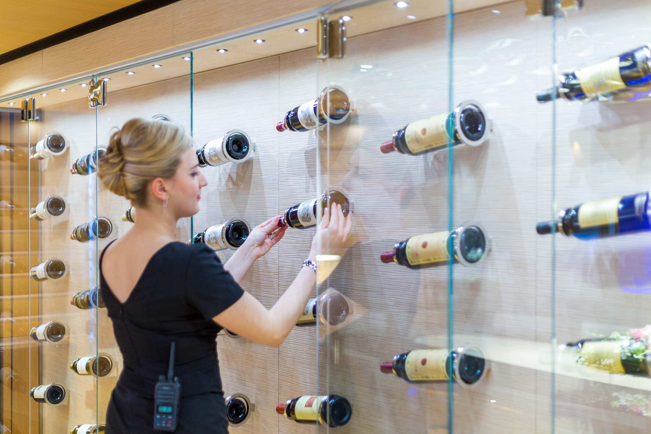 Stewardess placing bottle of fine wine in yacht's cellar