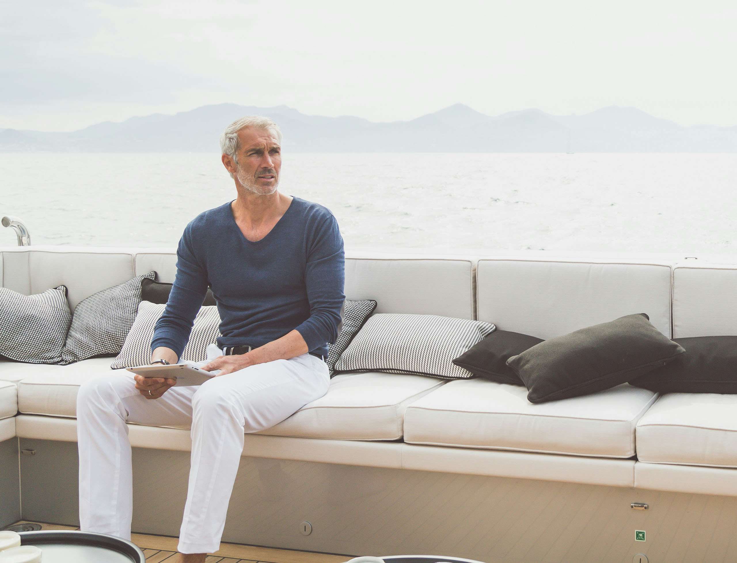 Yacht owner sitting on sundeck with tablet in hand