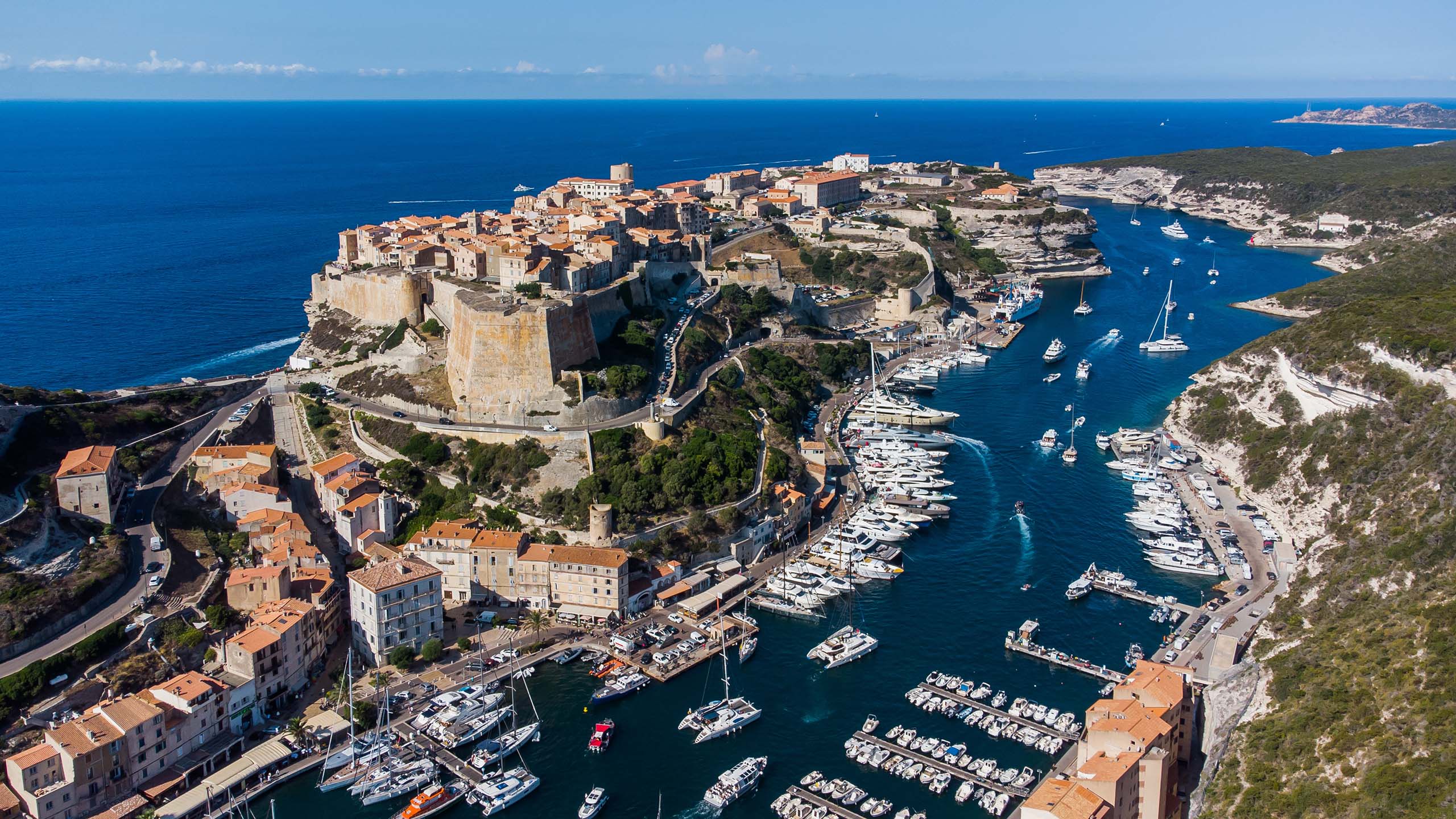 Bird's-eye view of Bonifacio's marina and cape at Corsica's southern tip in France - An ancient citadel perched atop a cliff promontory, commanding views over the Mediterranean Sea.